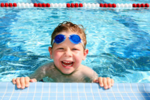 Summer safety; Smiling six year old boy in a sunny swimming pool
