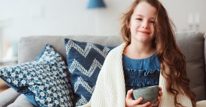 child girl drinking hot tea to recover from flu. Healing kids and protect immunity from seasonal virus, health concept; blog: keep kids healthy this winter