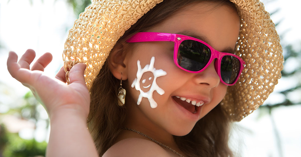 Happy child in glasses with sunscreen on the face; blog: 5 Sun Safety Tips for Kids