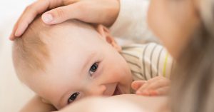 Newborn baby feeds mom's breast. Infant child boy eating and smiling; blog: 7 Places to Find Breastfeeding Support