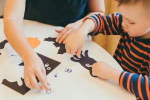 young mother with toddler son making craft spiders for halloween holiday family time