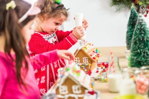 Kids decorating small gingerbread houses at the Christmas craft party.