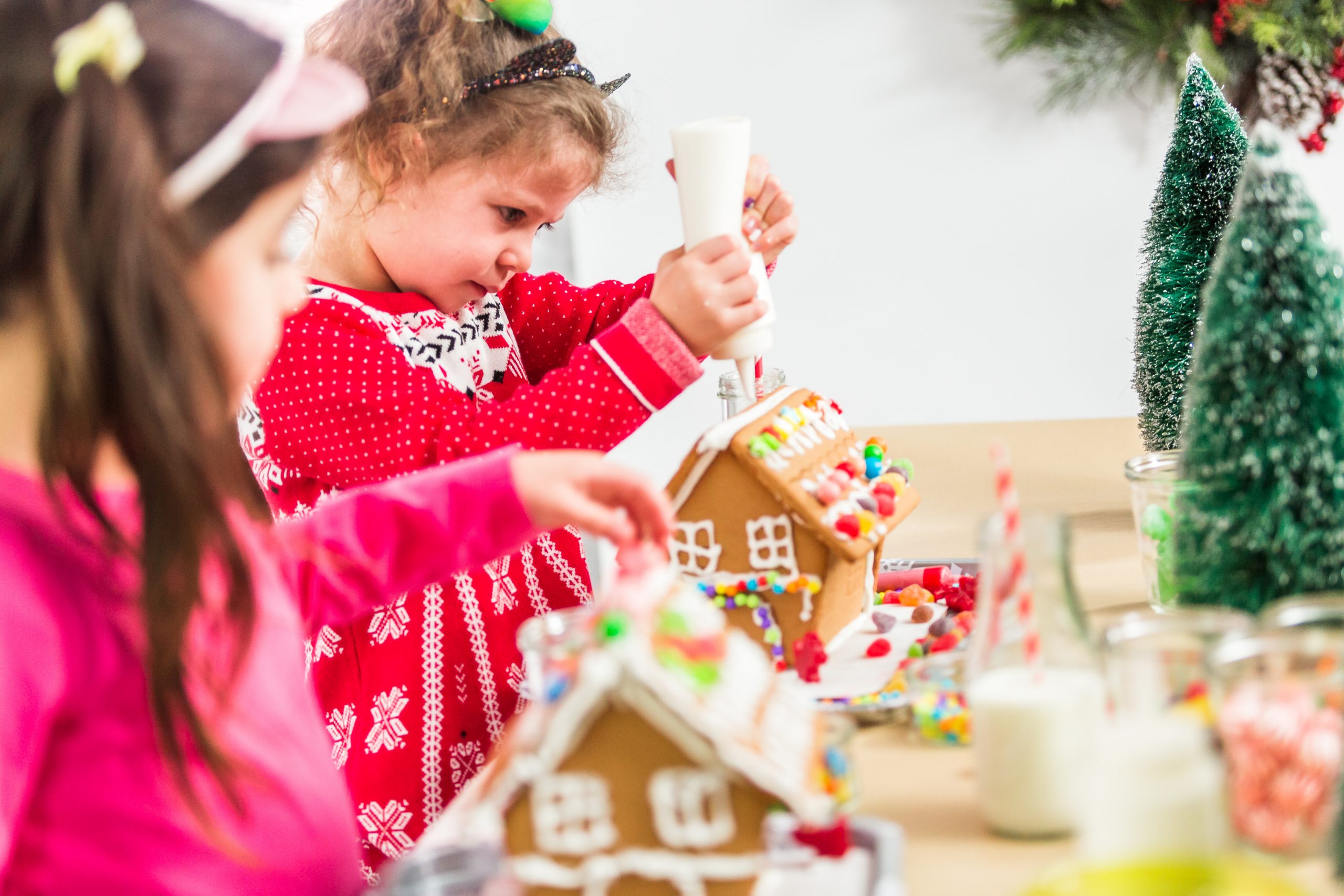 Kids decorating small gingerbread houses at the Christmas craft party.