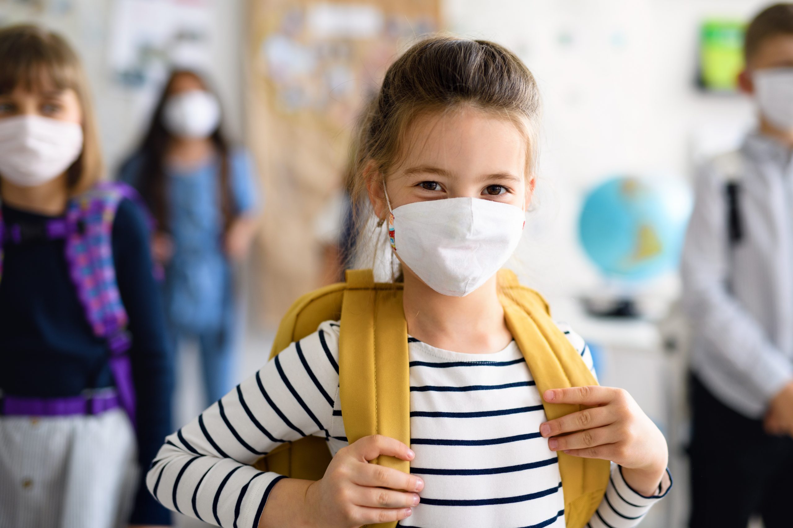 Front view of child with face mask going back to school after covid-19 quarantine and lockdown.