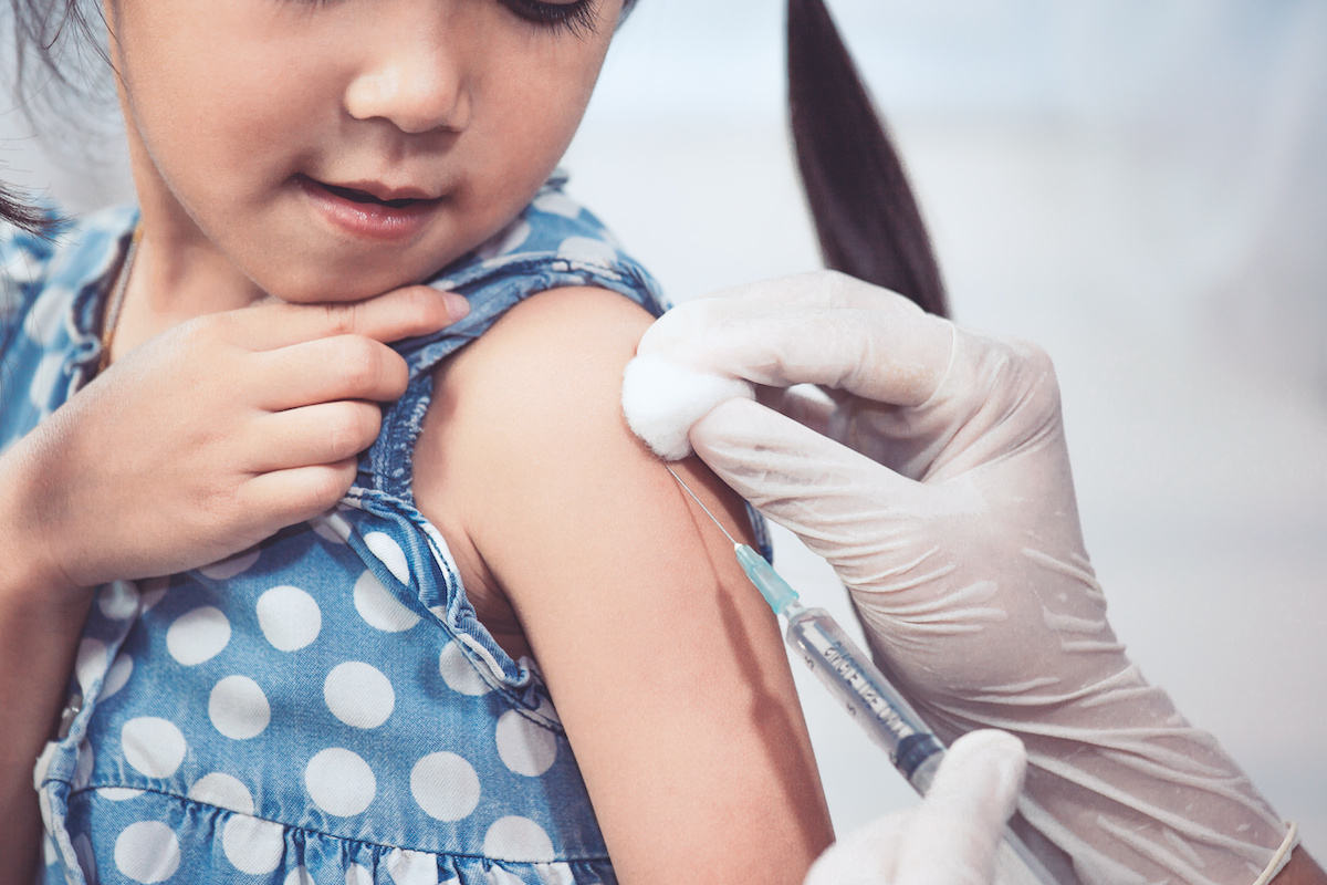 Doctor injecting vaccination in arm of asian little child girl,healthy and medical concept / blog - importance of childhood immunizations