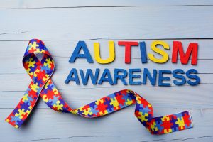 World Autism awareness and pride day or month with Puzzle pattern ribbon on blue wooden background. / blog - autism awareness month