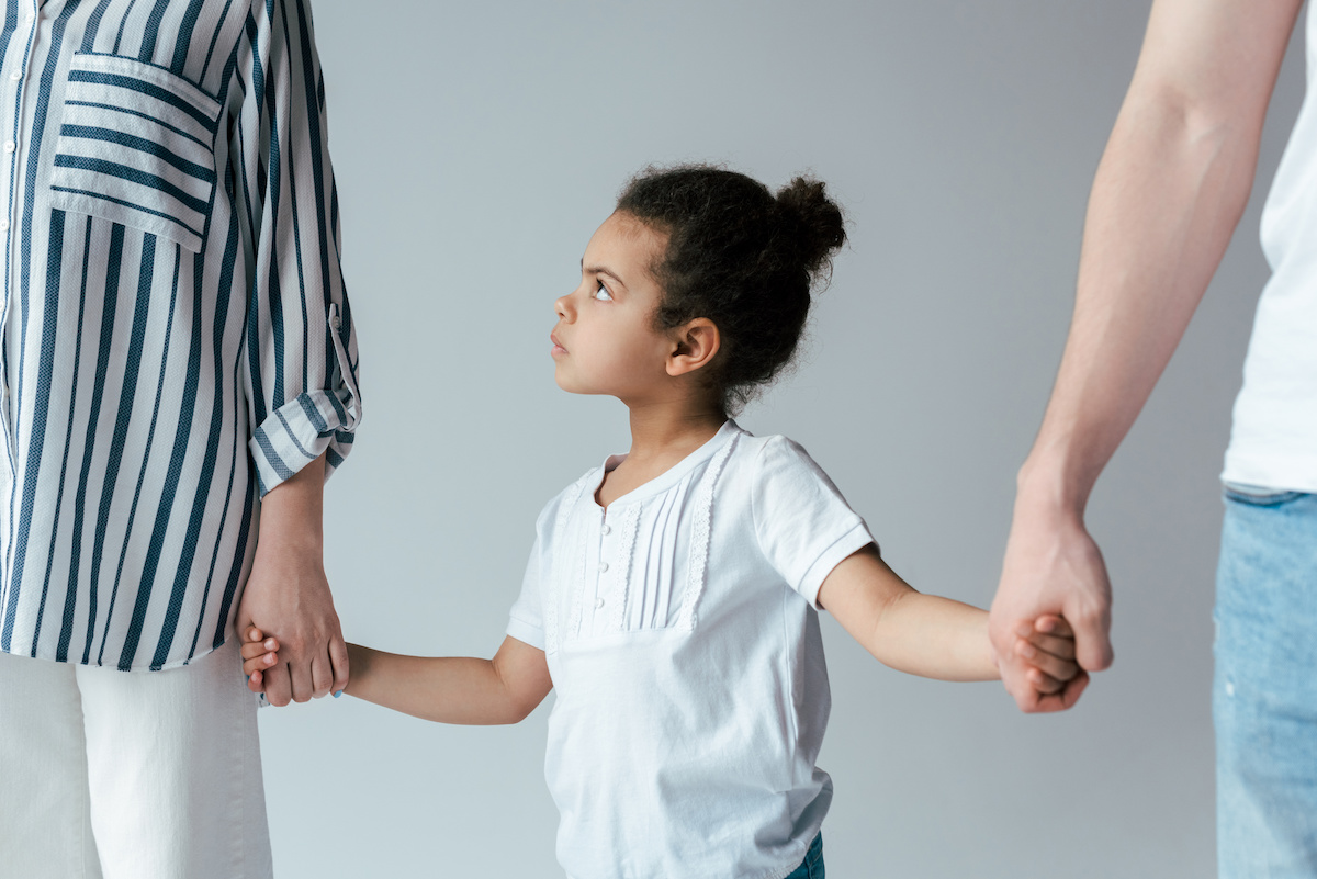 sad african american kid holding hands with divorced foster parents isolated on grey / blog - ways to co-parent